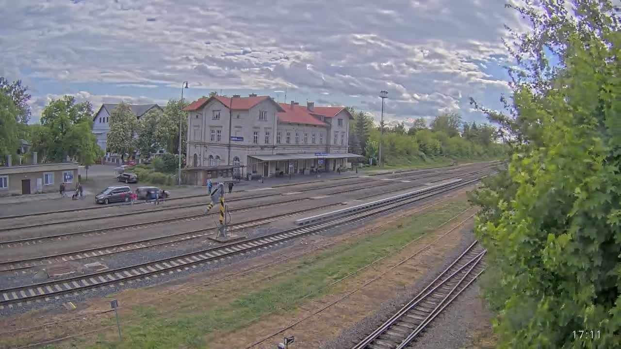 A long shot of a train station with several train tracks extending into the distance under a partly cloudy sky.