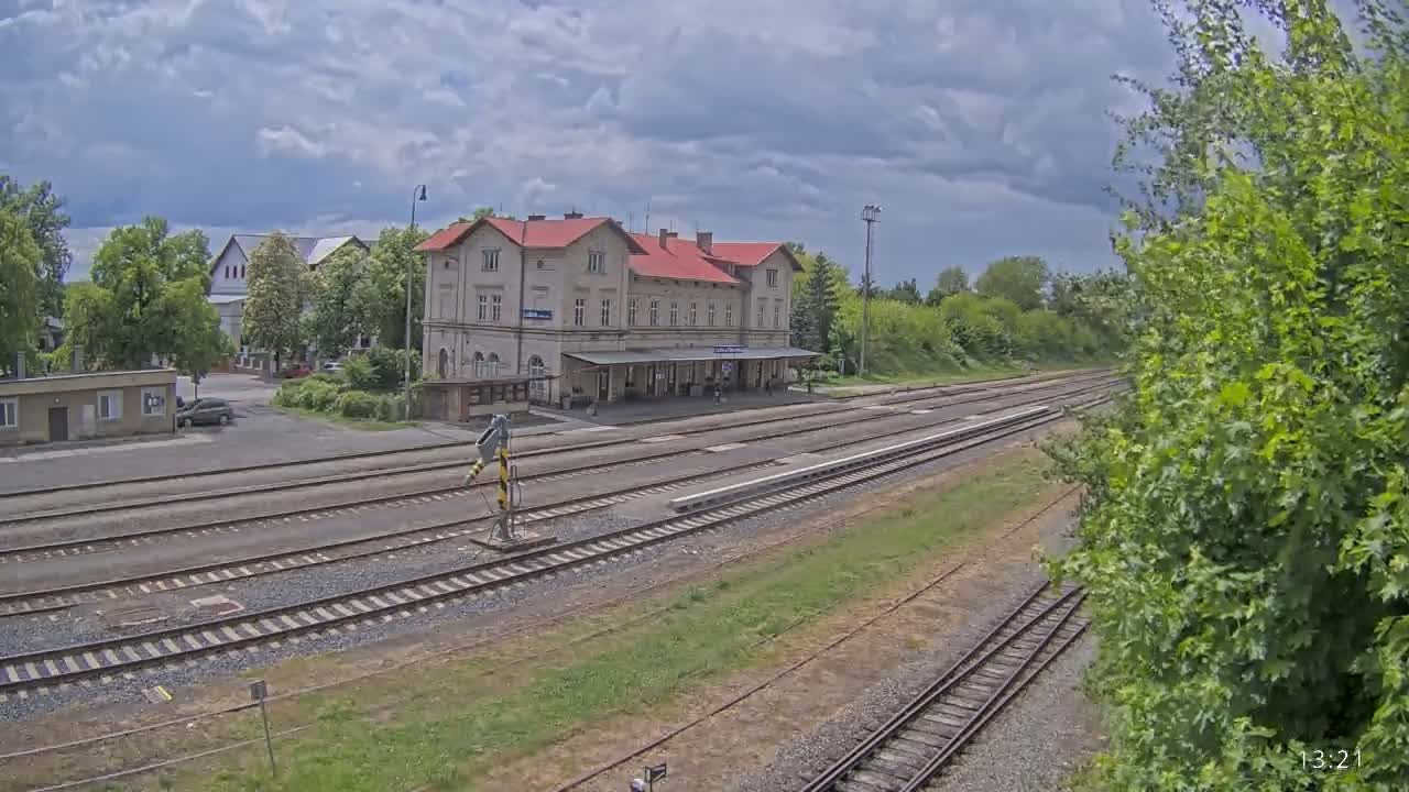 A train station with a long platform and several train tracks under a partly cloudy sky.