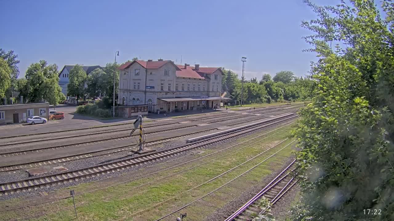 A long shot of a train station on a sunny day, showing several train tracks extending from a long building with a covered platform.
