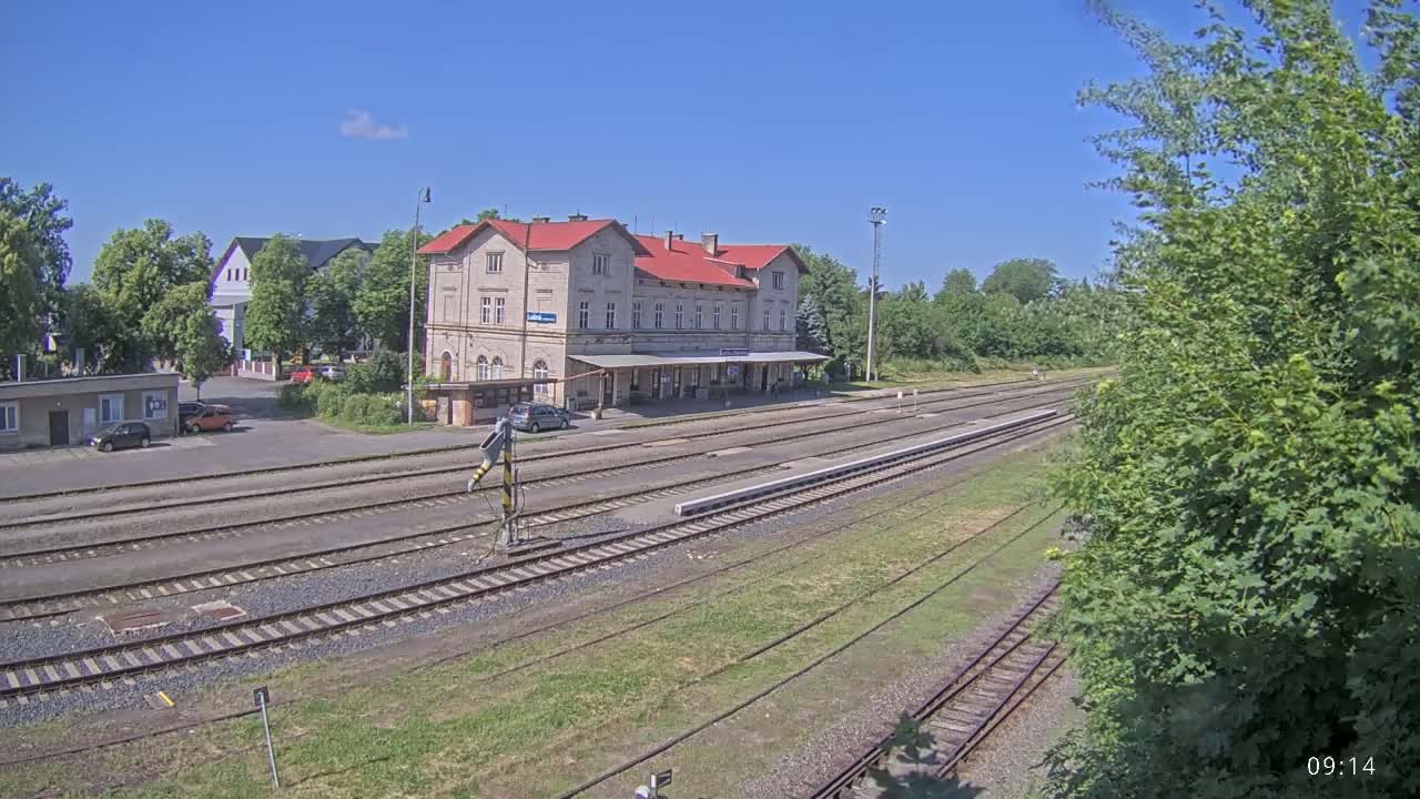 A long shot of a train station building and its surrounding railway tracks on a sunny day.