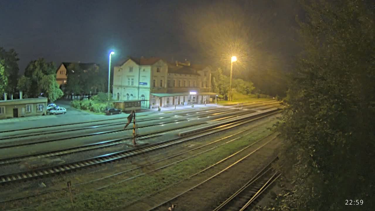 A nighttime view of a train station with multiple train tracks, illuminated by artificial lights under a dark sky.