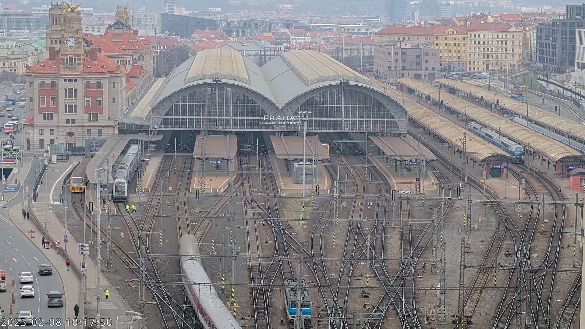 A large train station with numerous tracks and trains, under an overcast sky.