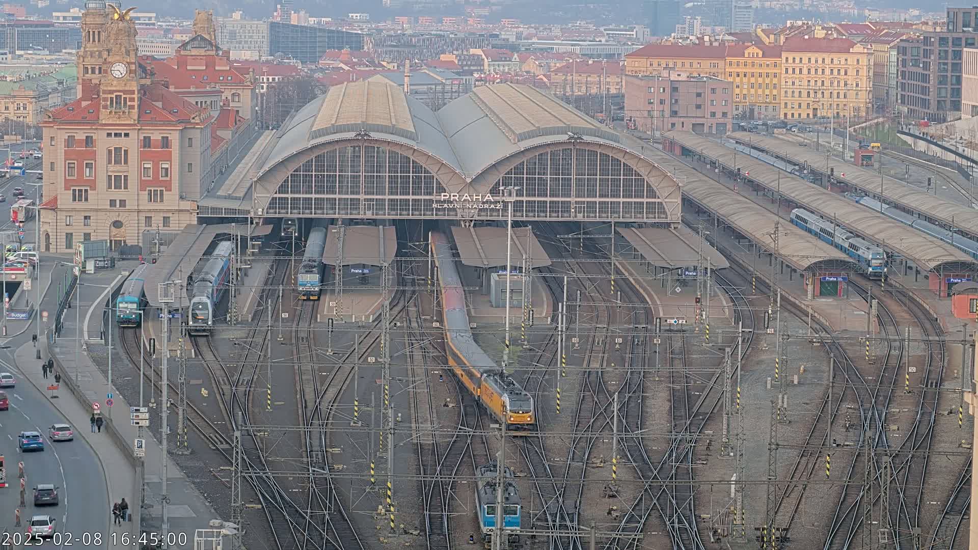 A large train station with numerous trains and tracks, viewed from above on an overcast day.