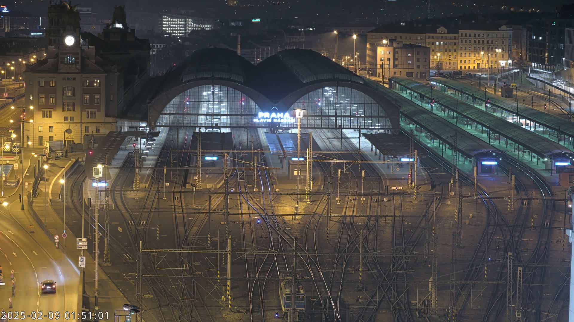 A large, illuminated train station with numerous tracks and platforms at night.