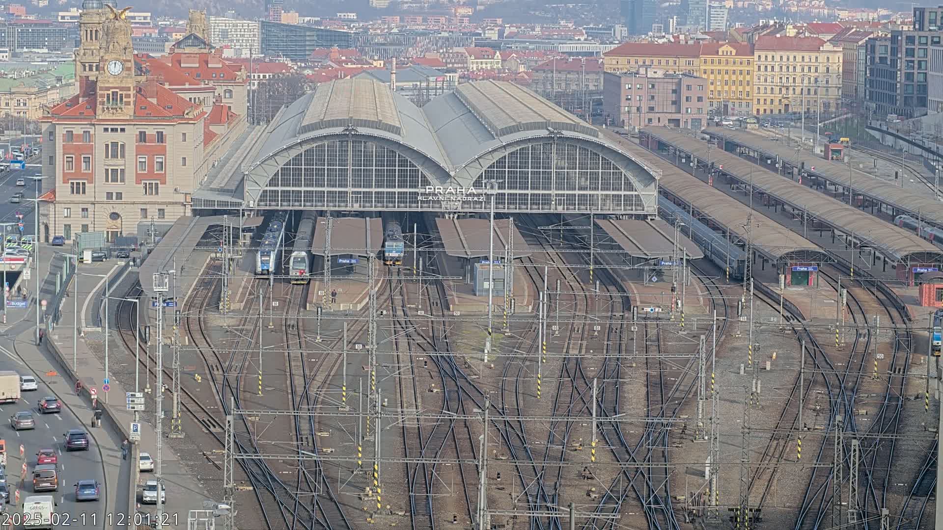 A large train station with many tracks and several trains, viewed from above on a clear day.