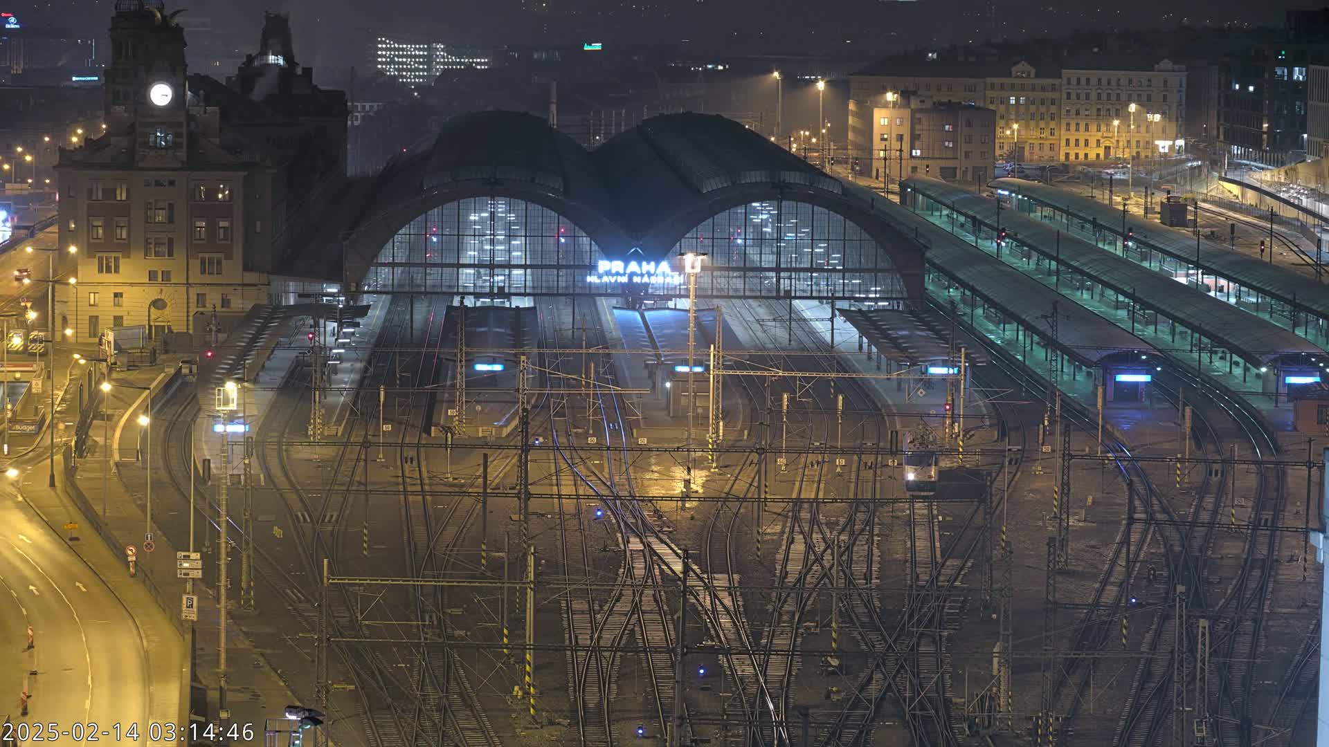 A nighttime aerial view of a large, illuminated train station with numerous tracks and platforms.