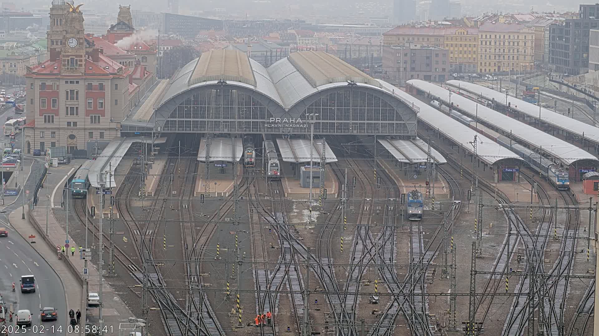 A large train station with numerous tracks and several trains visible under an overcast sky.
