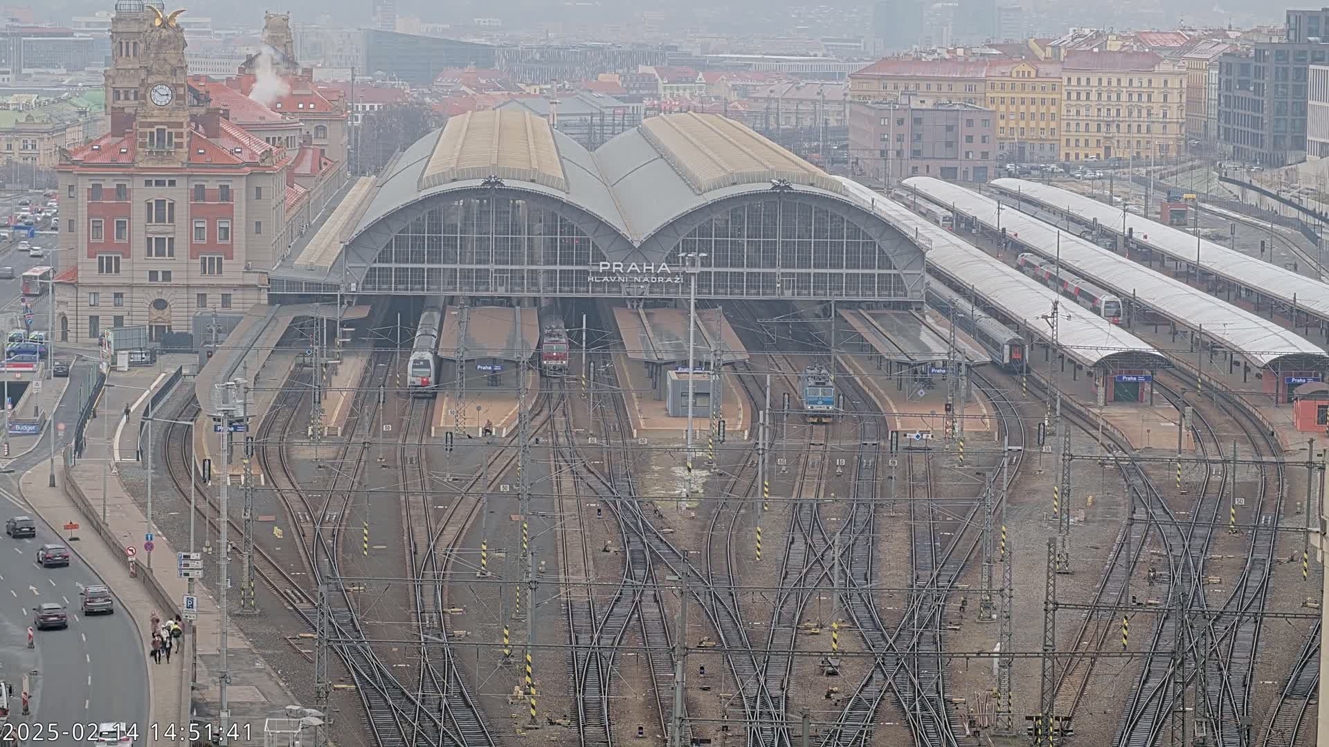 A large train station with numerous tracks and trains, under an overcast sky.