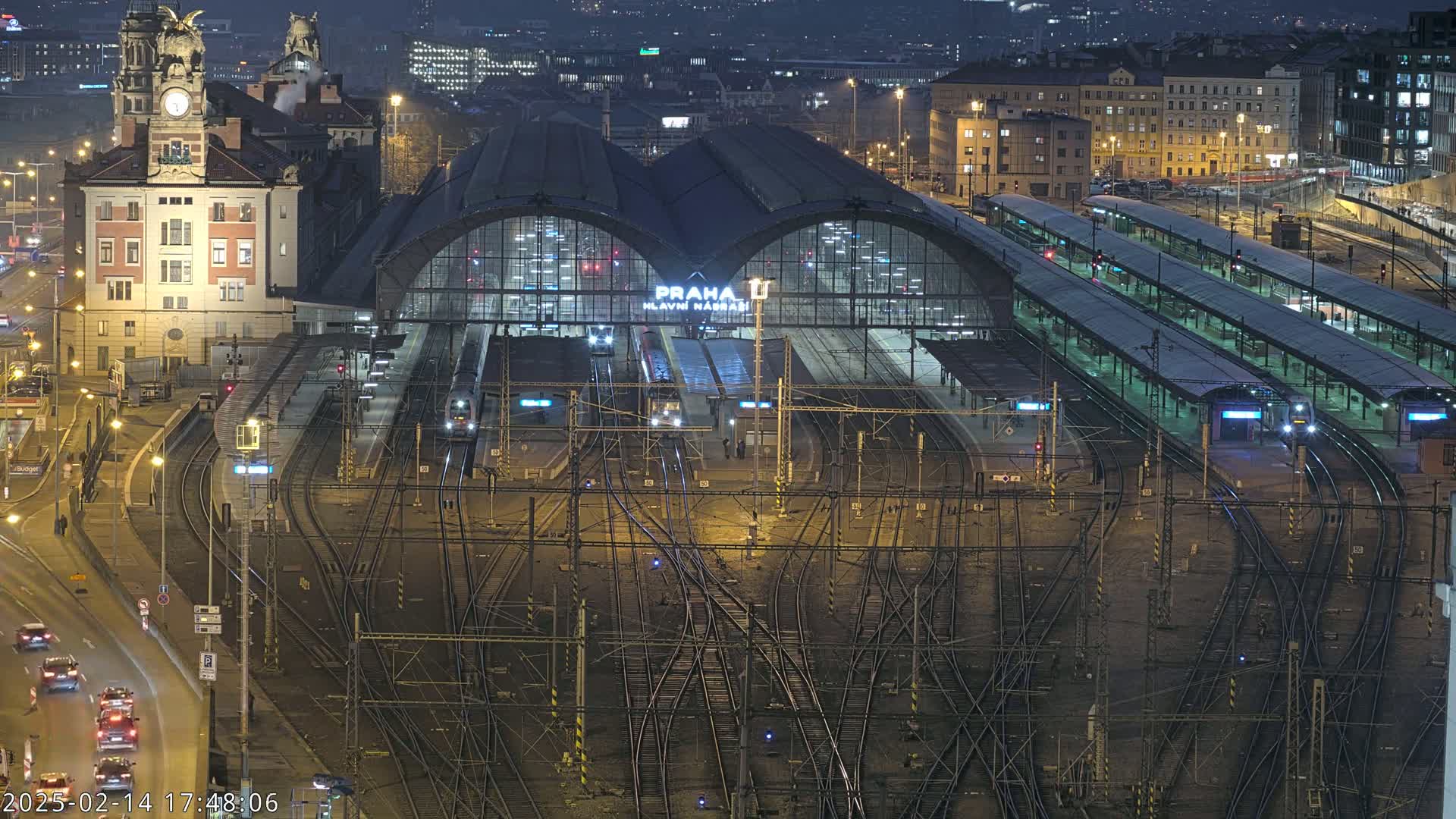 A nighttime view of a large train station with numerous tracks and platforms, lit by artificial lights.