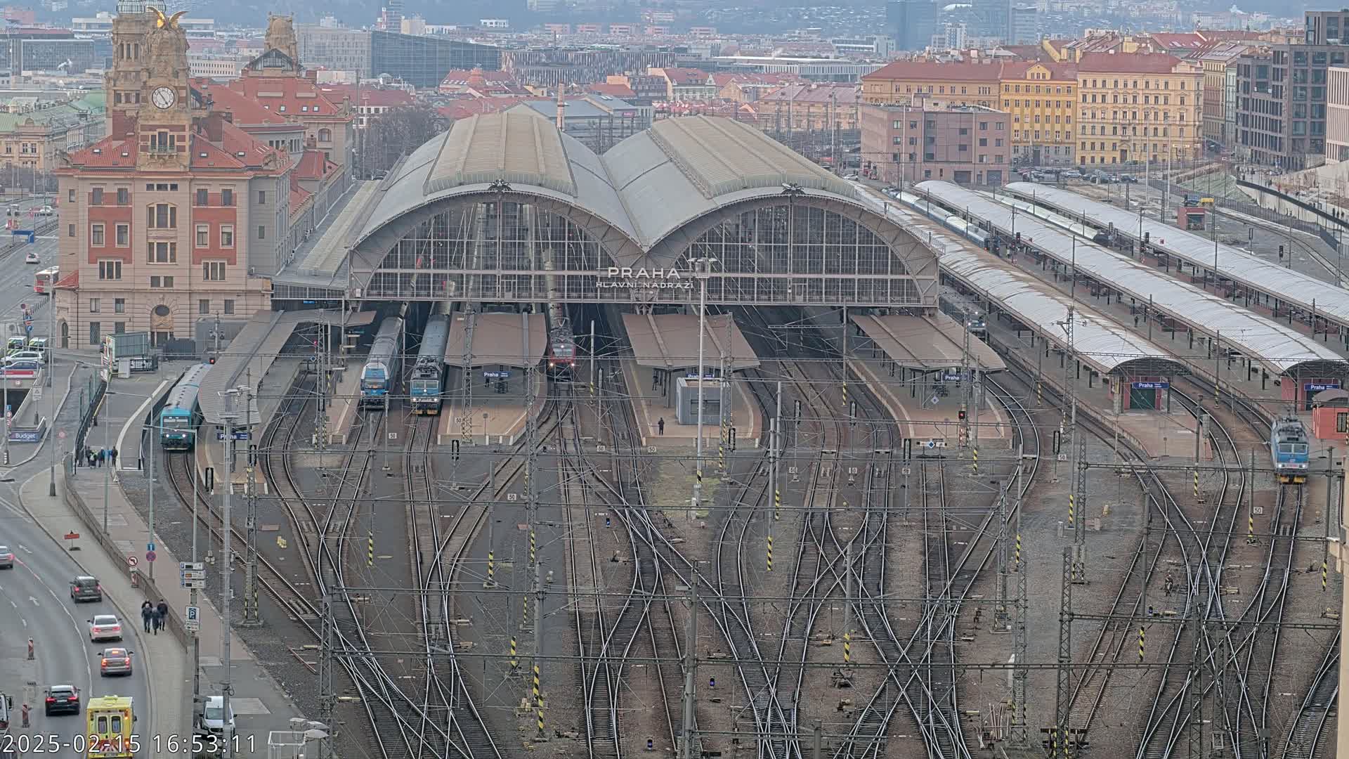 A large train station with numerous tracks and trains, viewed from above on an overcast day.