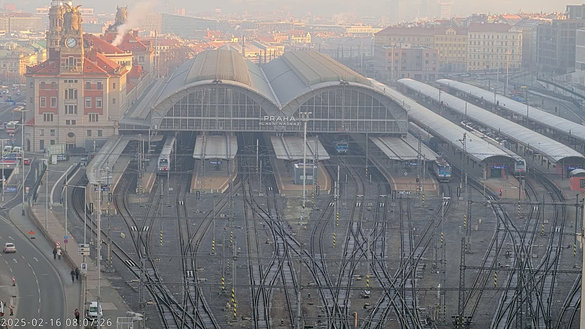 A large train station with many tracks and trains, under hazy conditions.