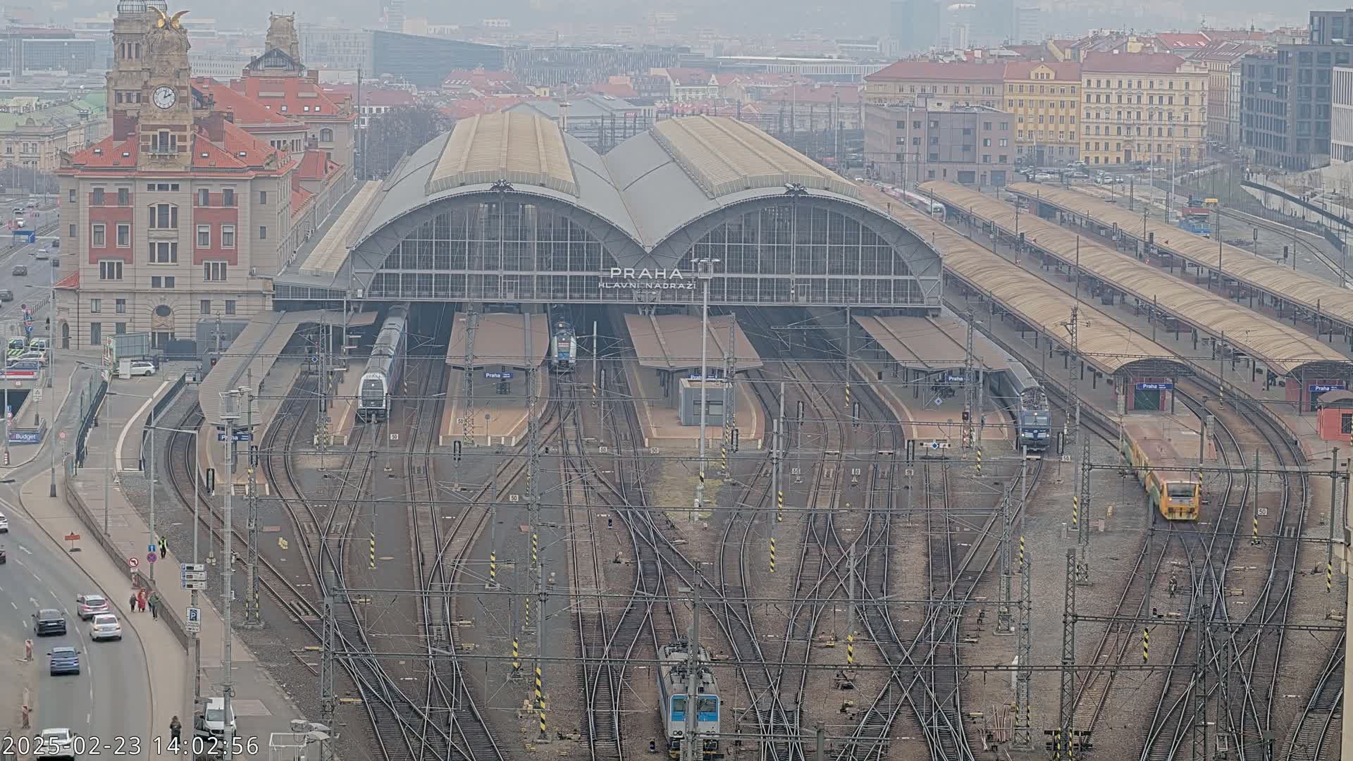 A large train station with numerous tracks and trains, viewed from above on an overcast day.