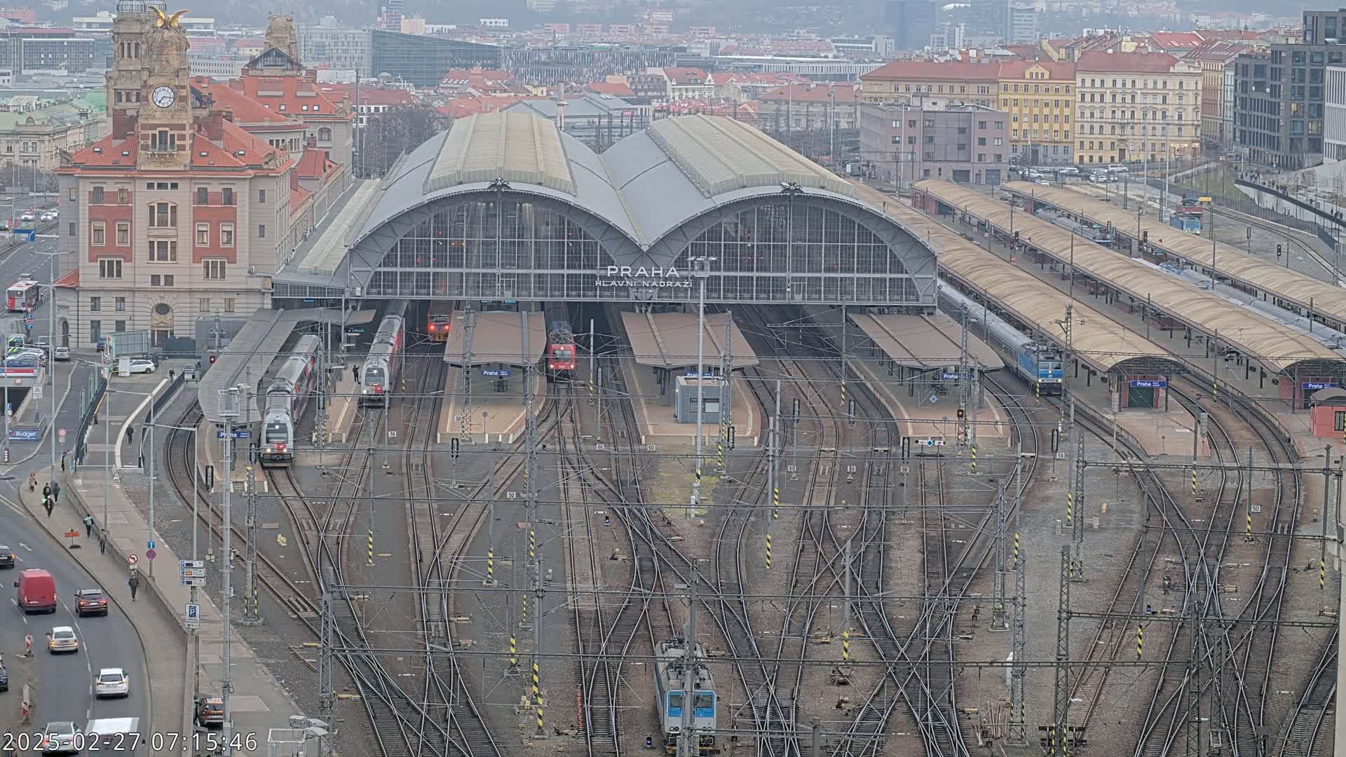 An aerial view of a large train station with numerous tracks and trains, on an overcast day.