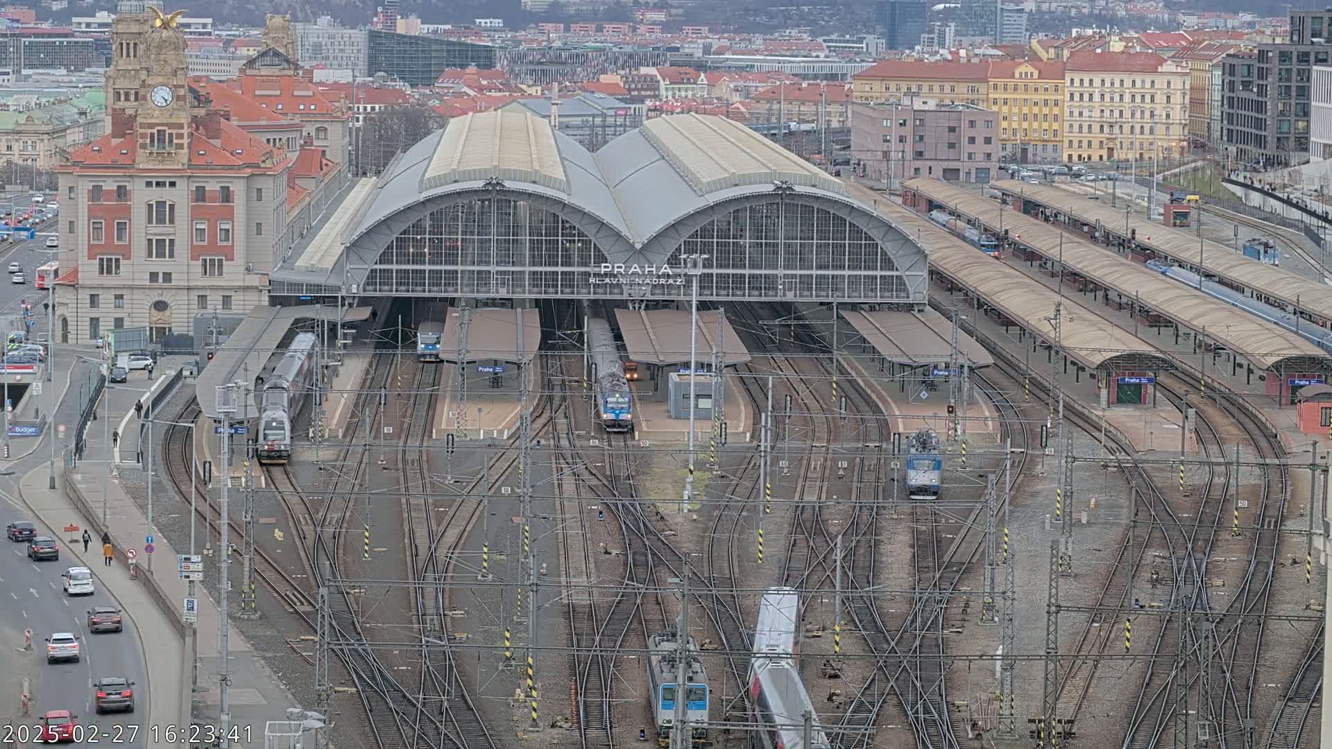 A large train station with many tracks and trains, under an overcast sky.