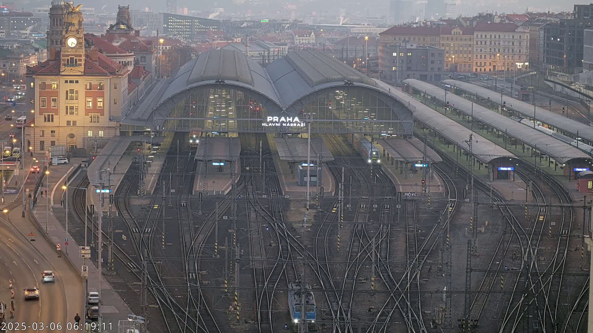 A large train station with many tracks and platforms is visible on an overcast day.