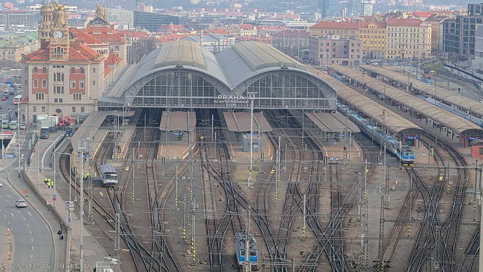 A large train station with many tracks and trains, viewed from above on a cloudy day.