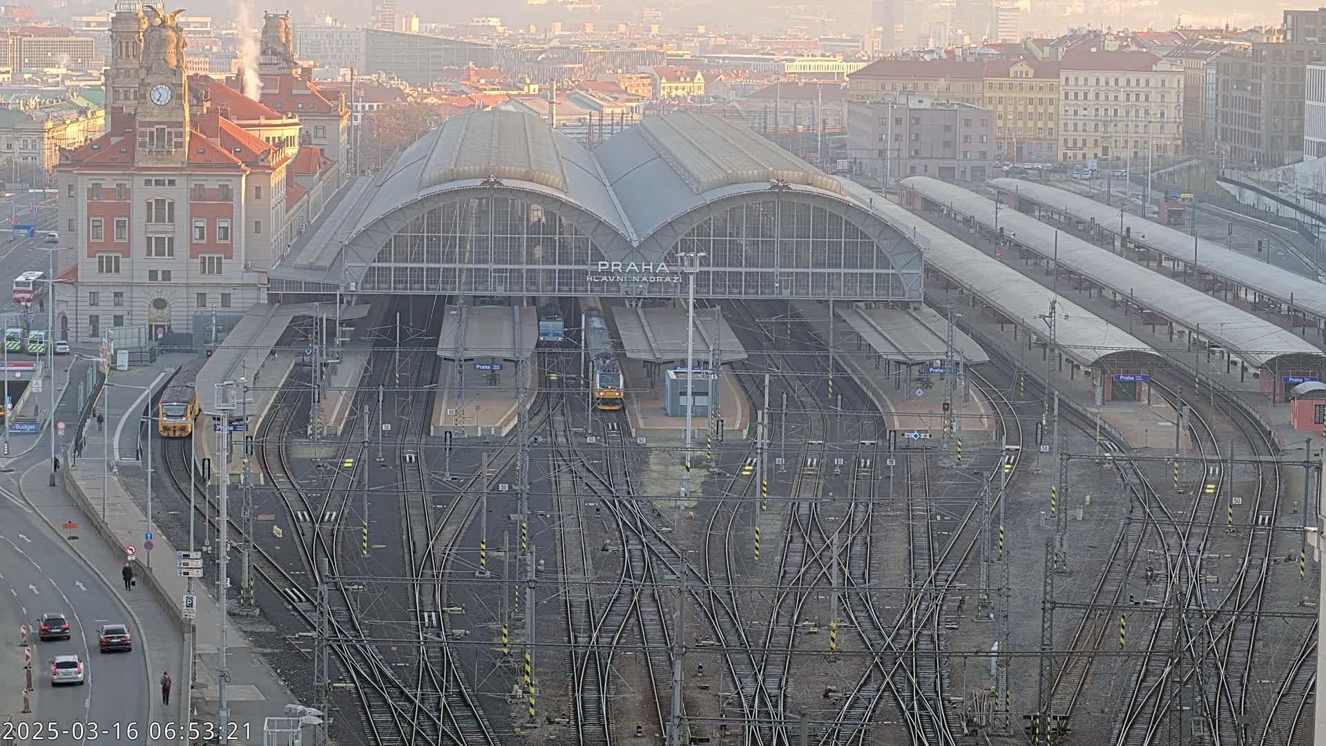 A large train station with numerous tracks and platforms is seen from an aerial view on a hazy day.