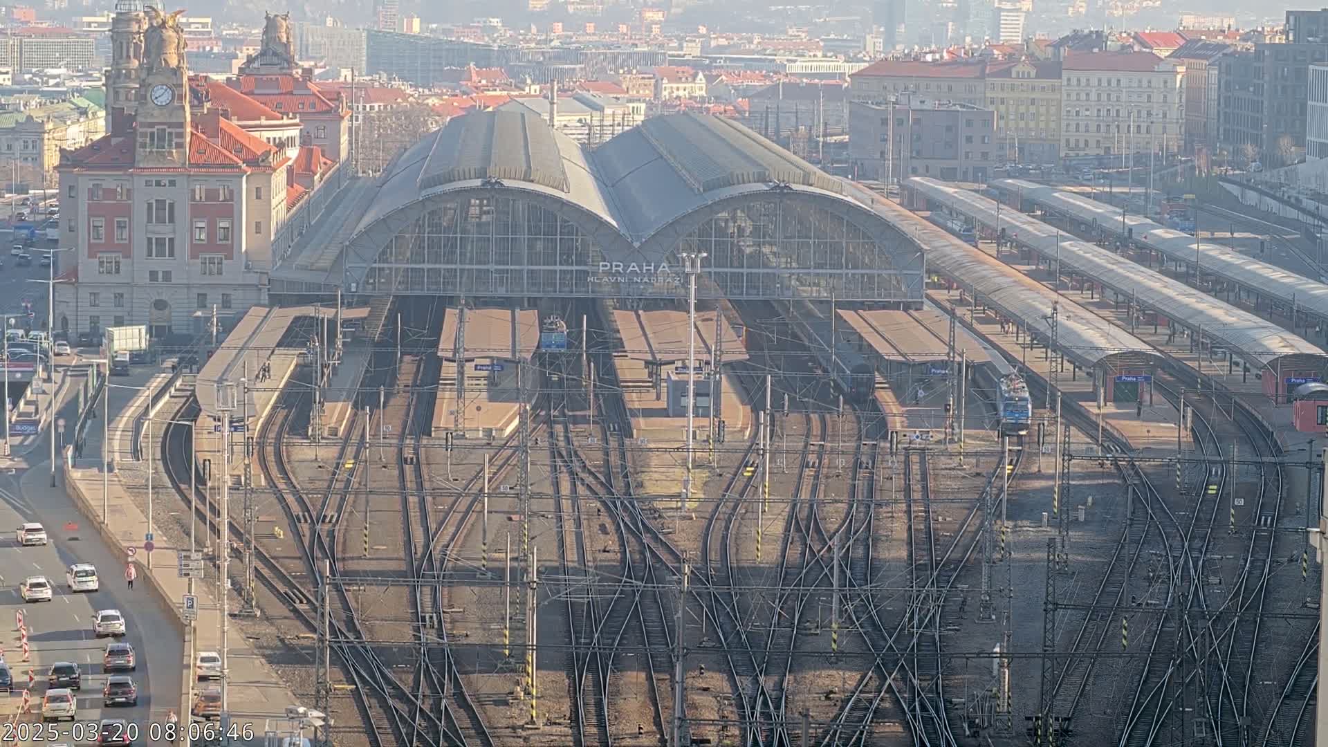 A large train station with many tracks and platforms, viewed from above on a sunny day.