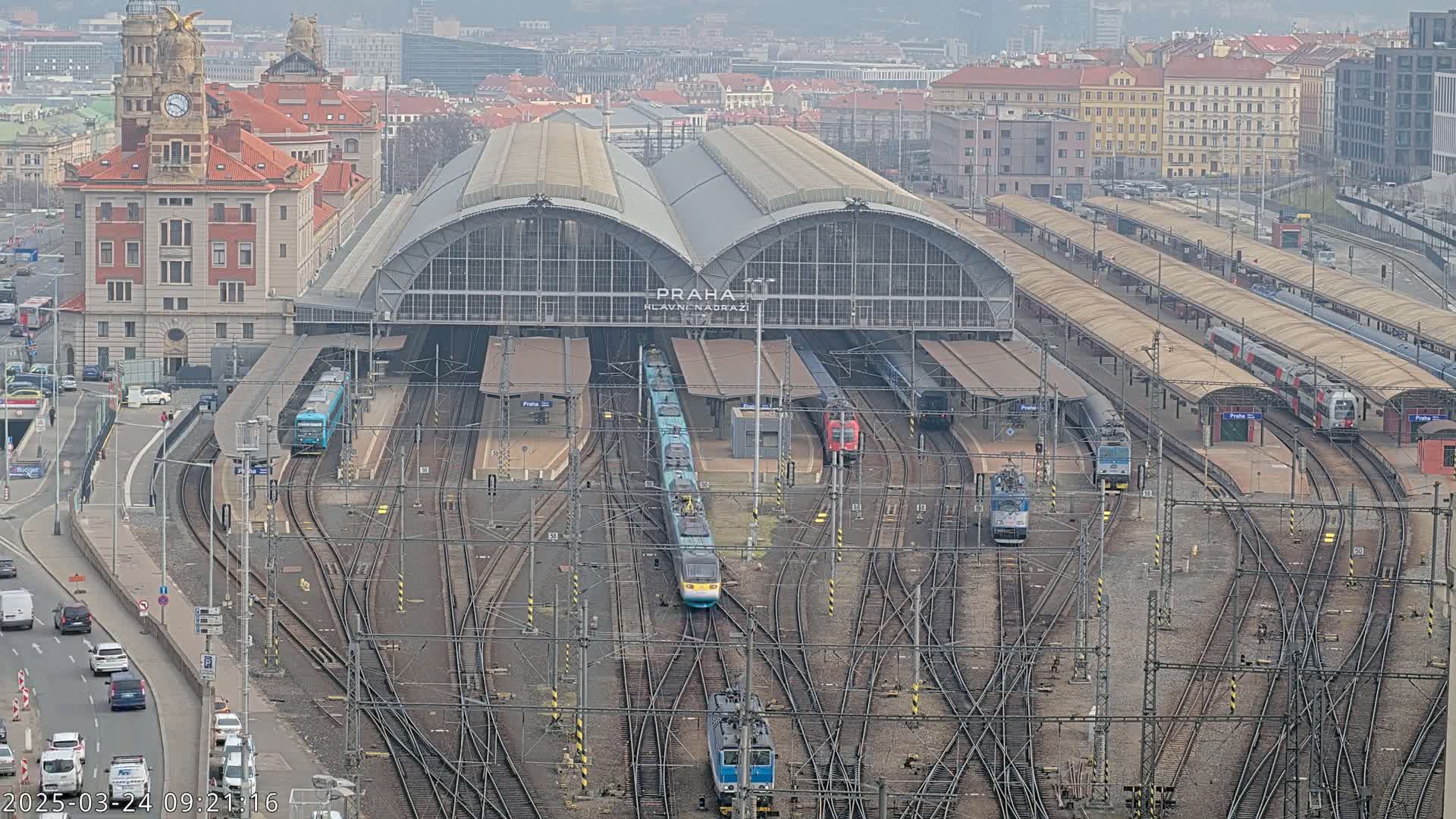 A large train station with numerous trains and tracks, viewed from above on an overcast day.