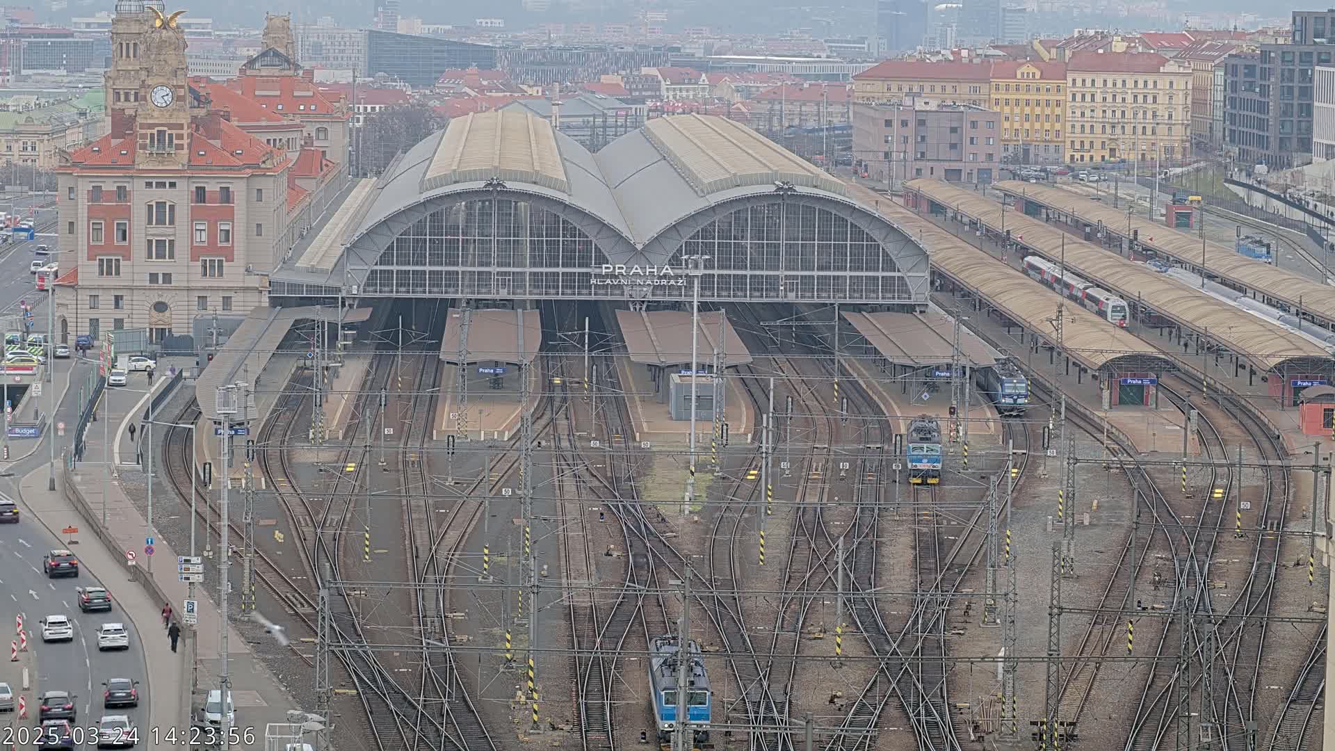A large train station with numerous tracks and trains, viewed from above on an overcast day.