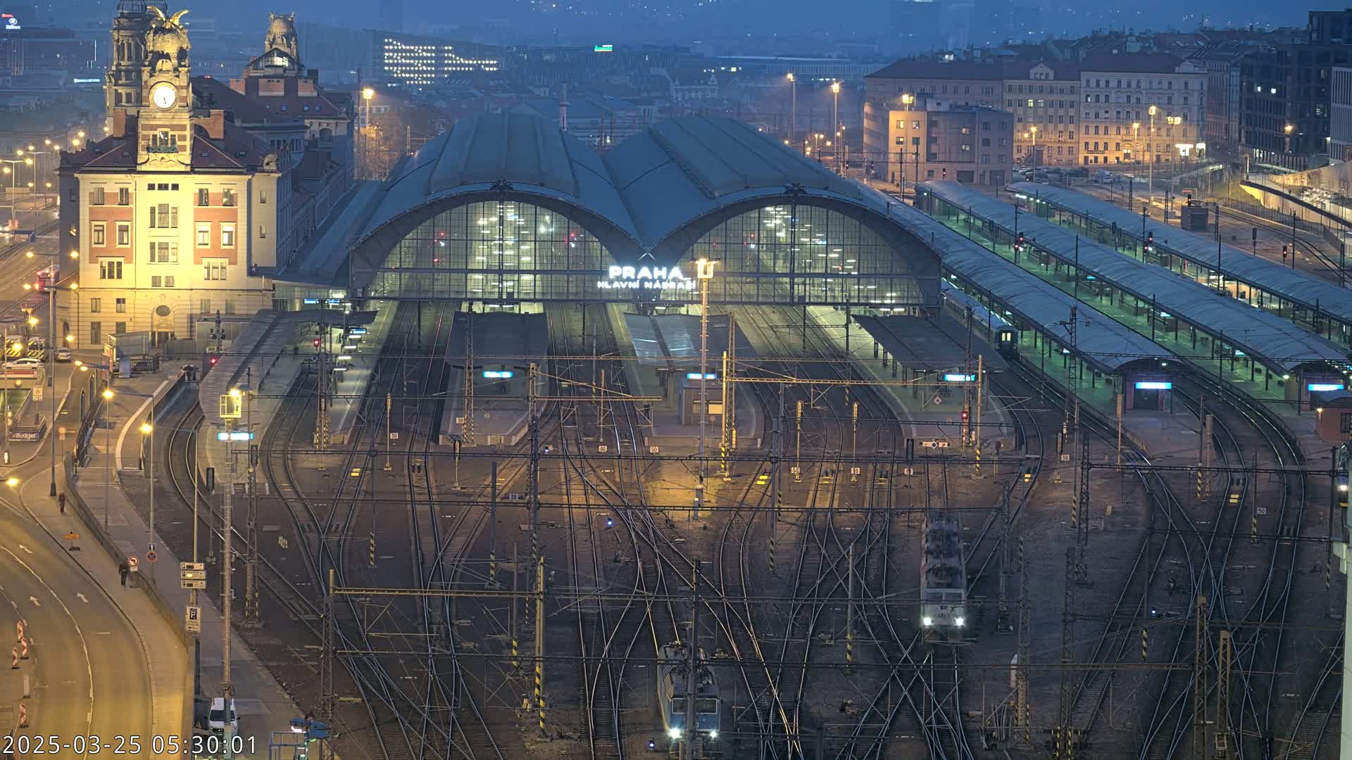 A large train station with many tracks and platforms at night, under a twilight sky.