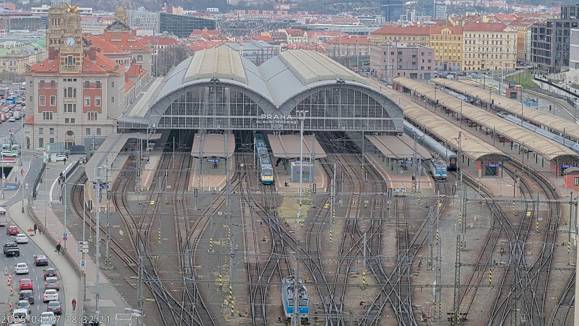 A large train station with many tracks and several trains, viewed from above on an overcast day.