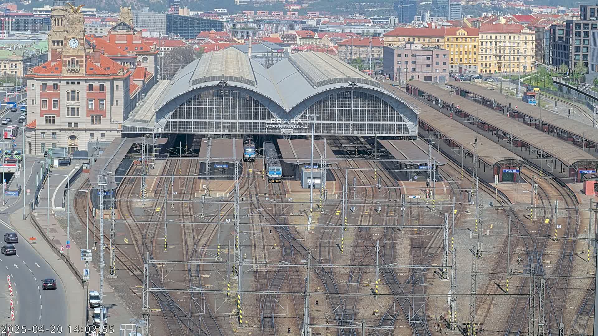 A large train station with numerous tracks and platforms, viewed from above on a sunny day.