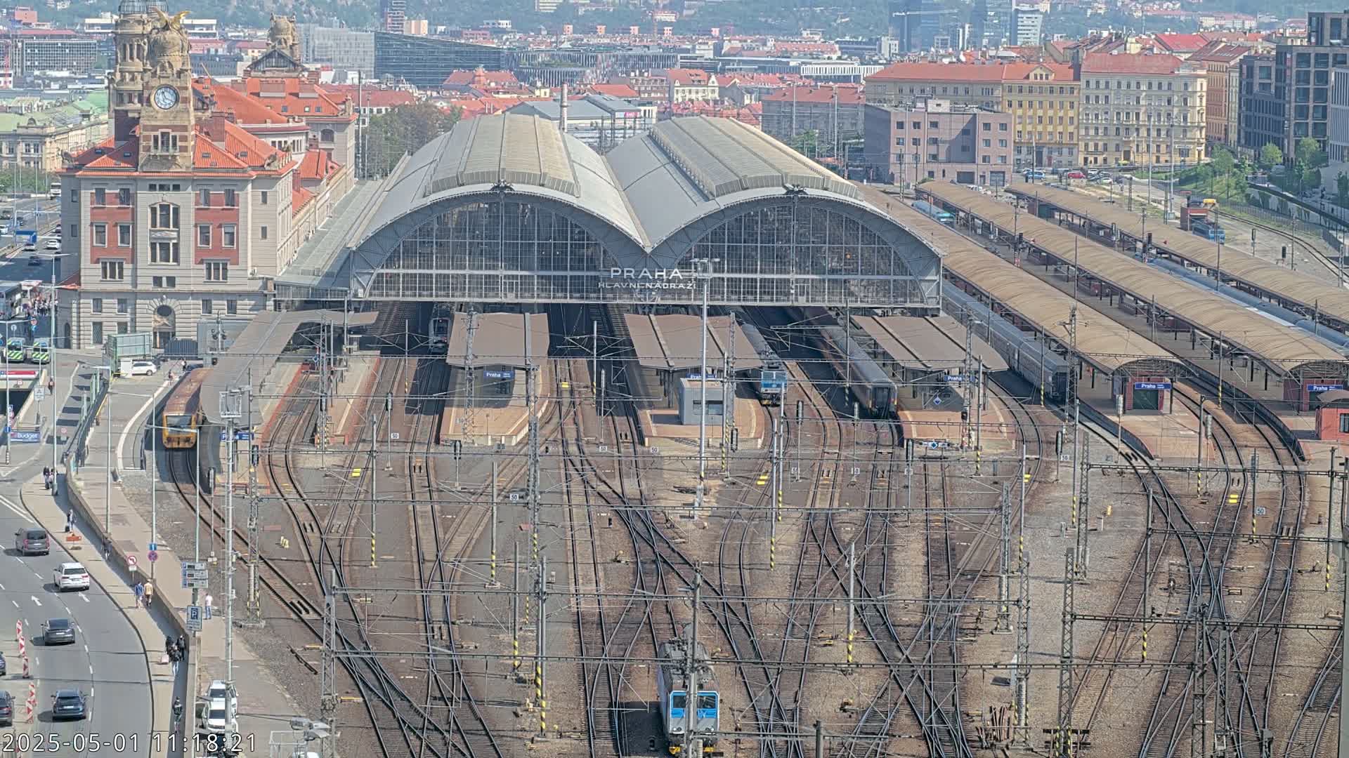 A large train station with many tracks and trains under a sunny sky.