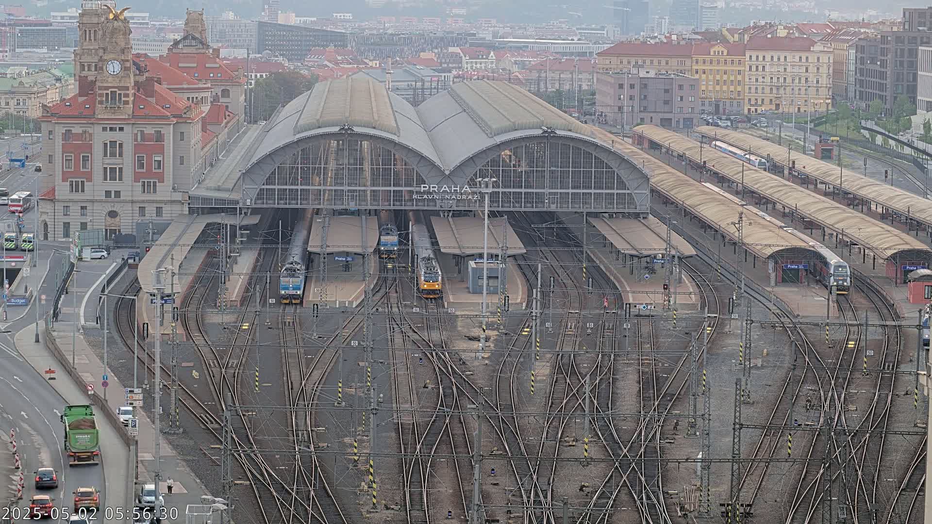 A large train station with numerous tracks and several trains, viewed from above on an overcast day.