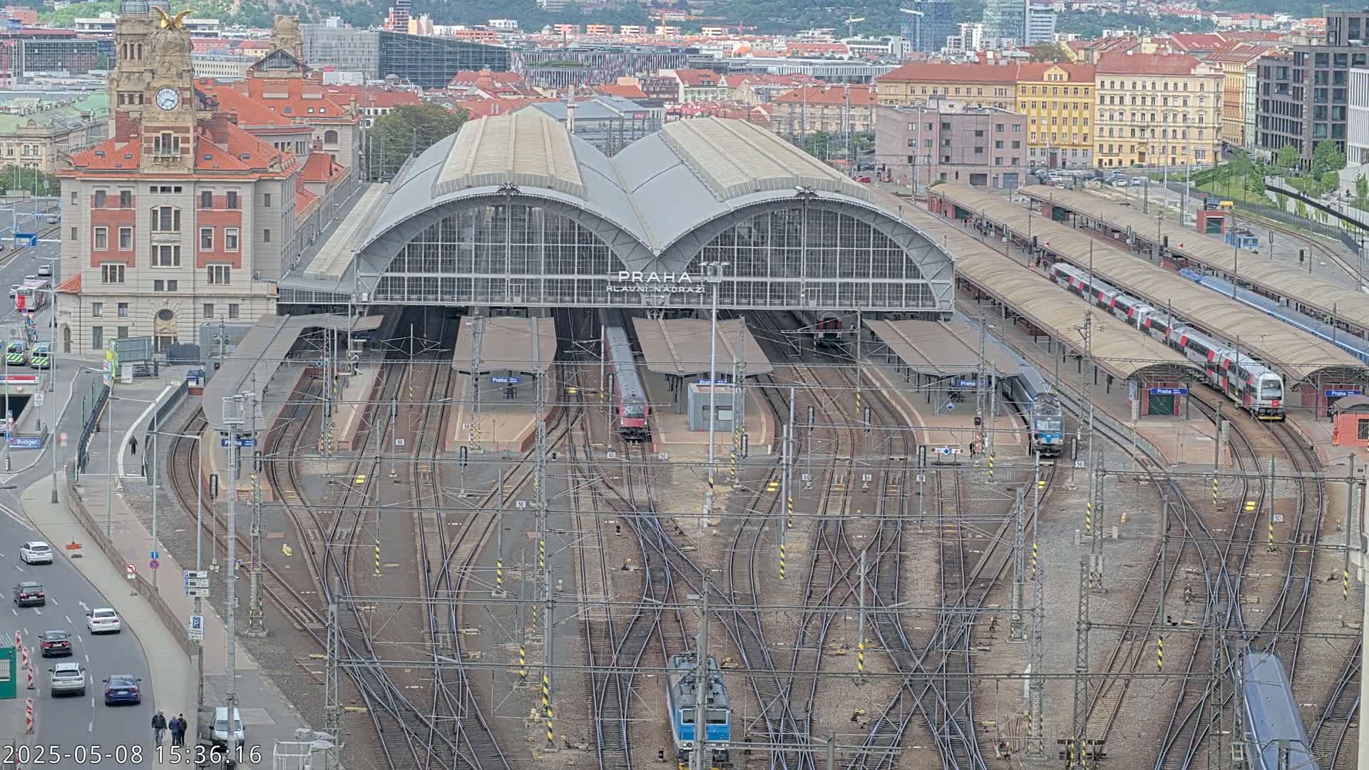A large train station with numerous tracks and several trains, viewed from above on an overcast day.