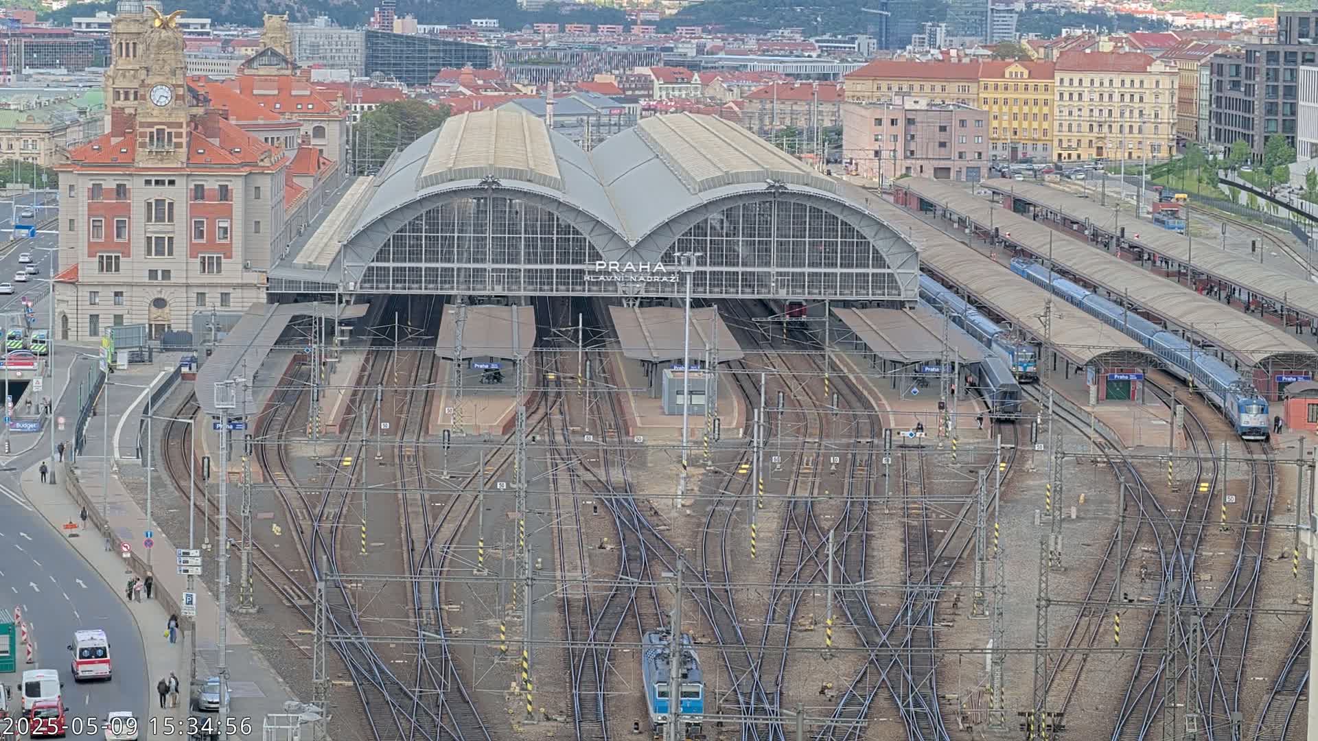 An aerial view shows a large train station with numerous tracks and trains, under an overcast sky.