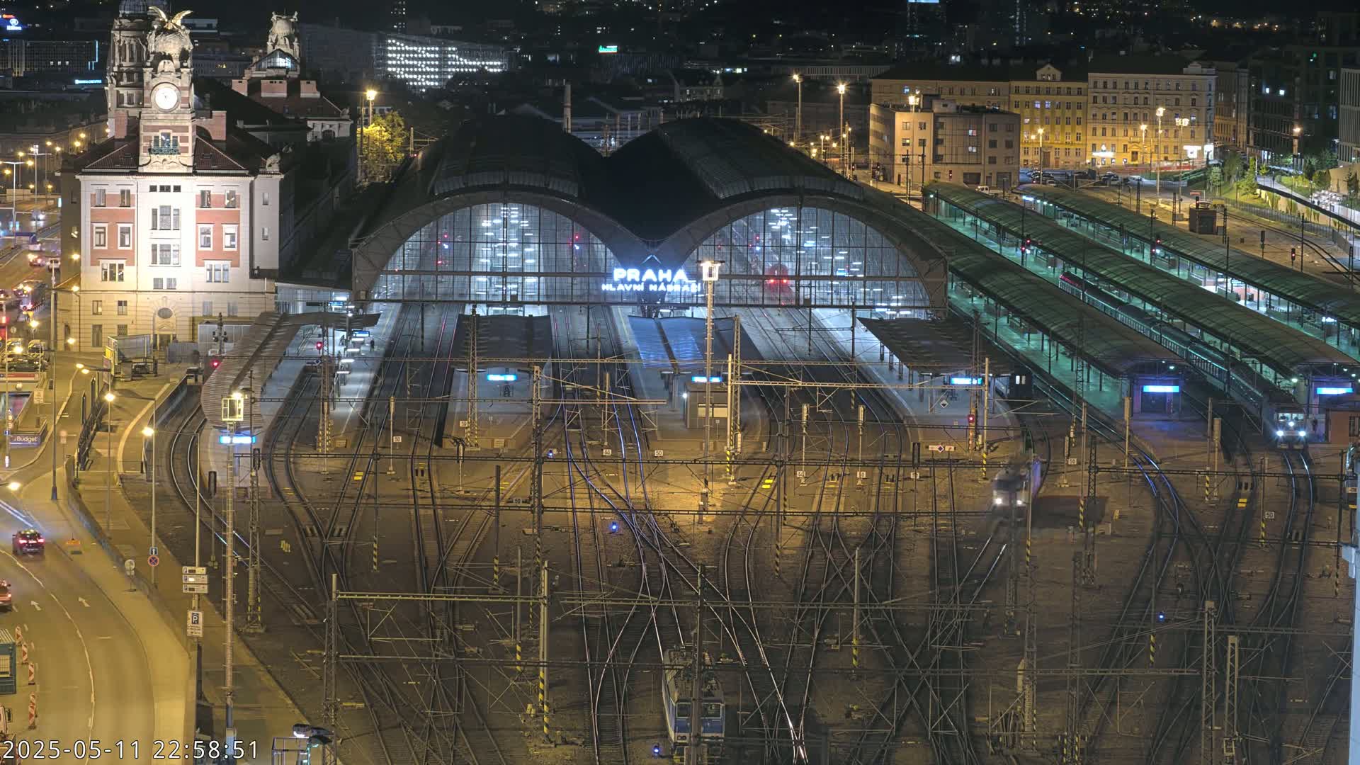 A nighttime, aerial view of a large, illuminated train station with many tracks and trains.