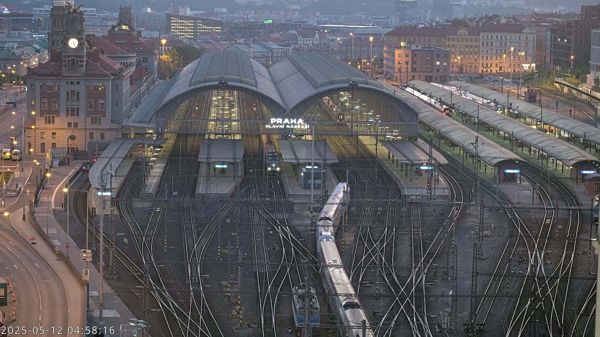 A large train station with numerous tracks and platforms, under a twilight sky.
