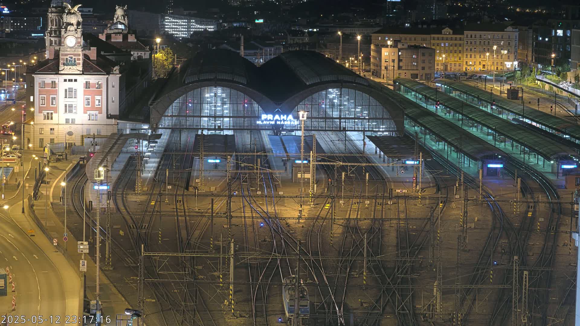 A nighttime aerial view of a large, illuminated train station with numerous tracks and platforms.
