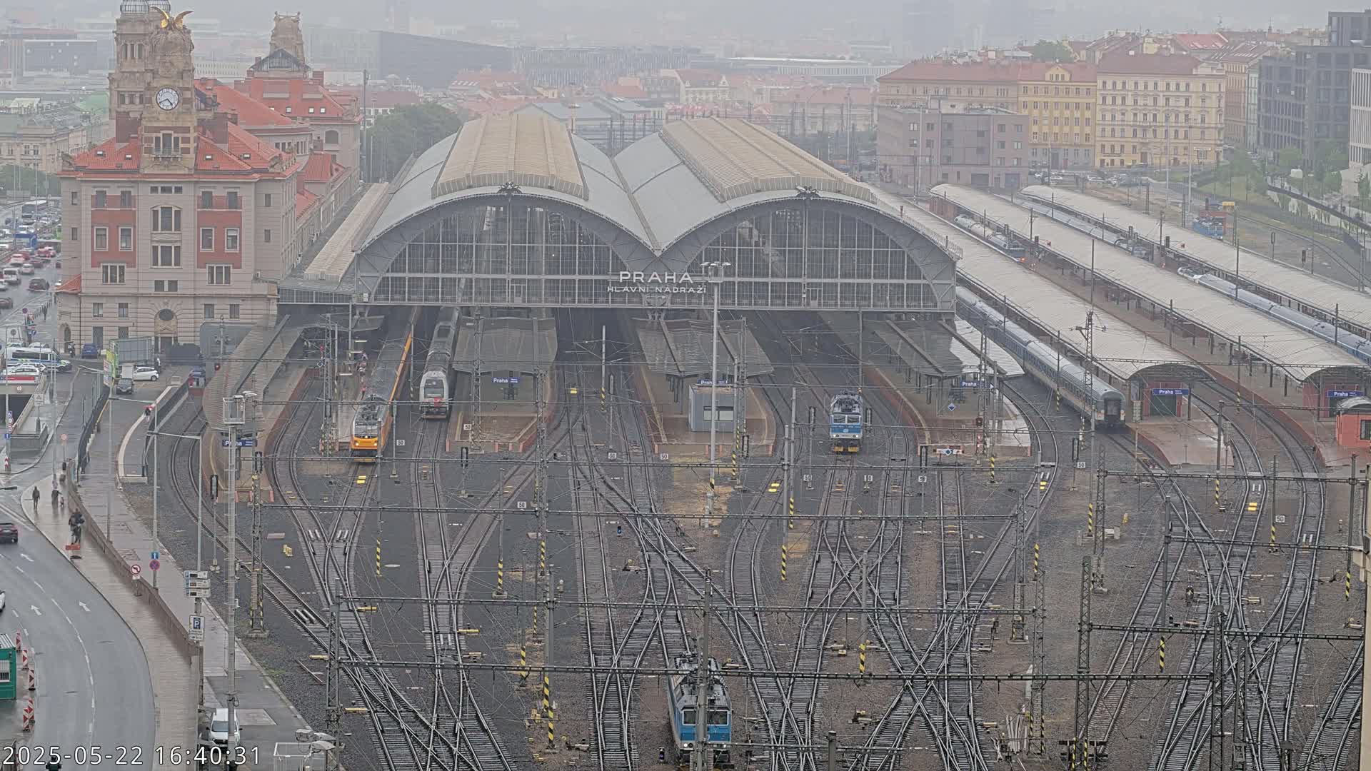 A large train station with numerous tracks and trains under an overcast sky.