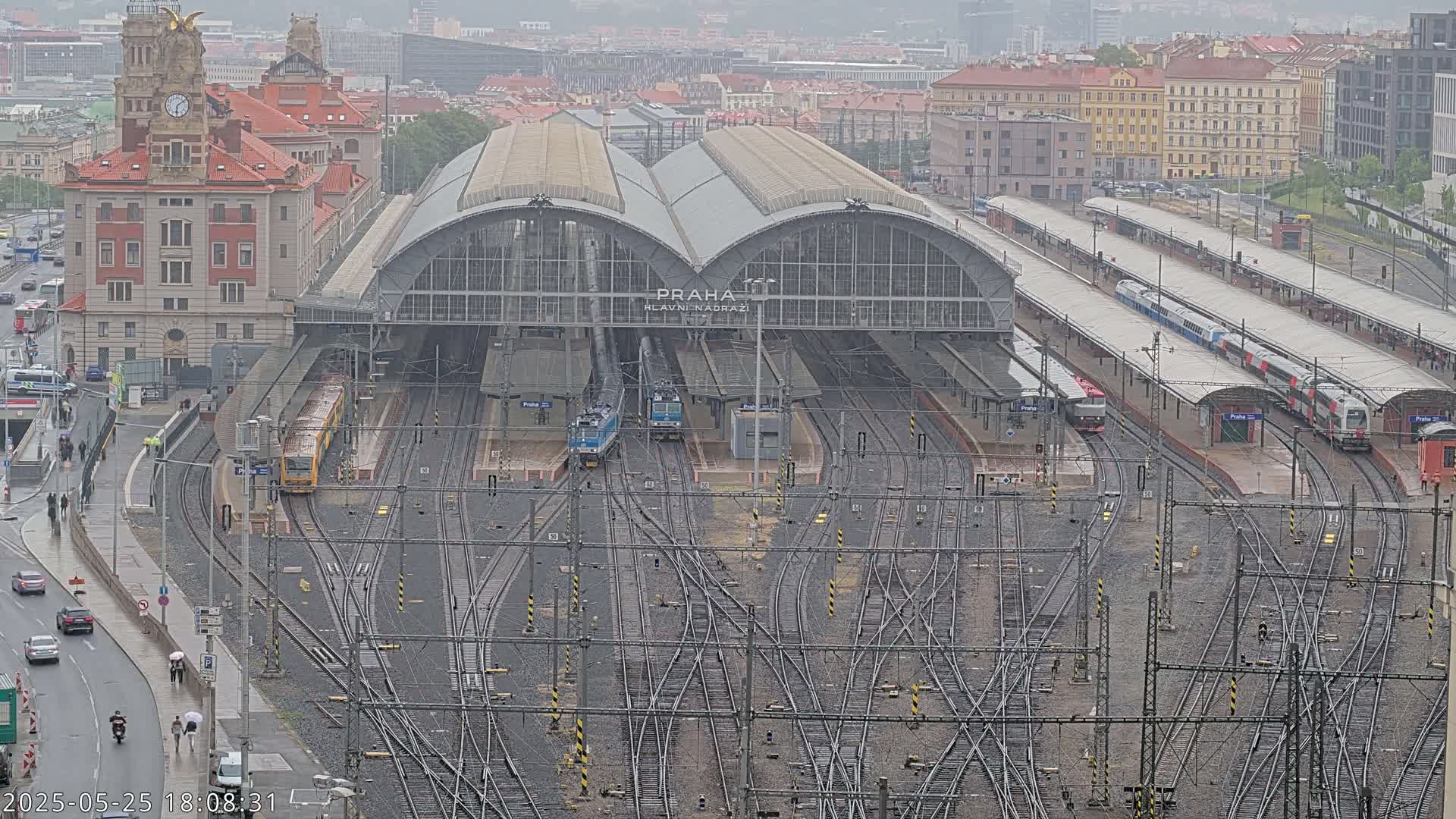 A large train station with many tracks and several trains, viewed from above on a rainy day.