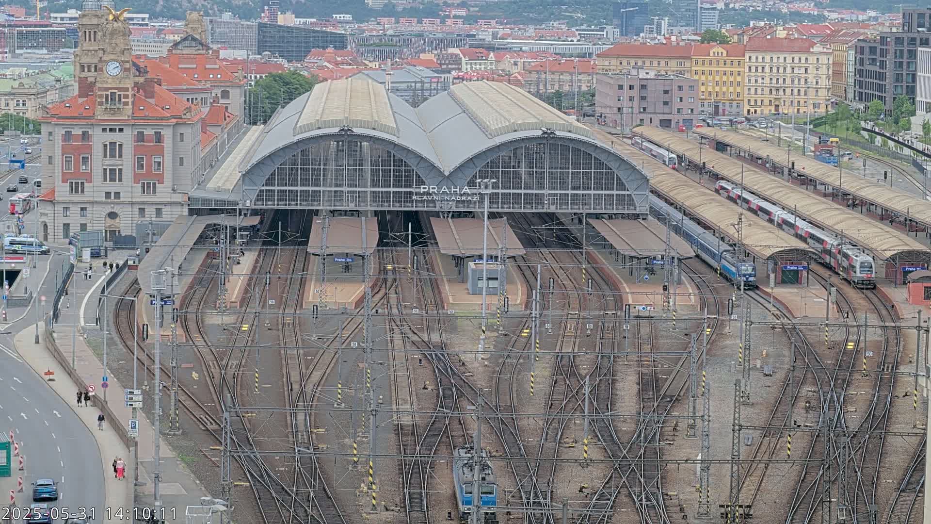 An aerial view of a large train station with numerous tracks and trains under an overcast sky.