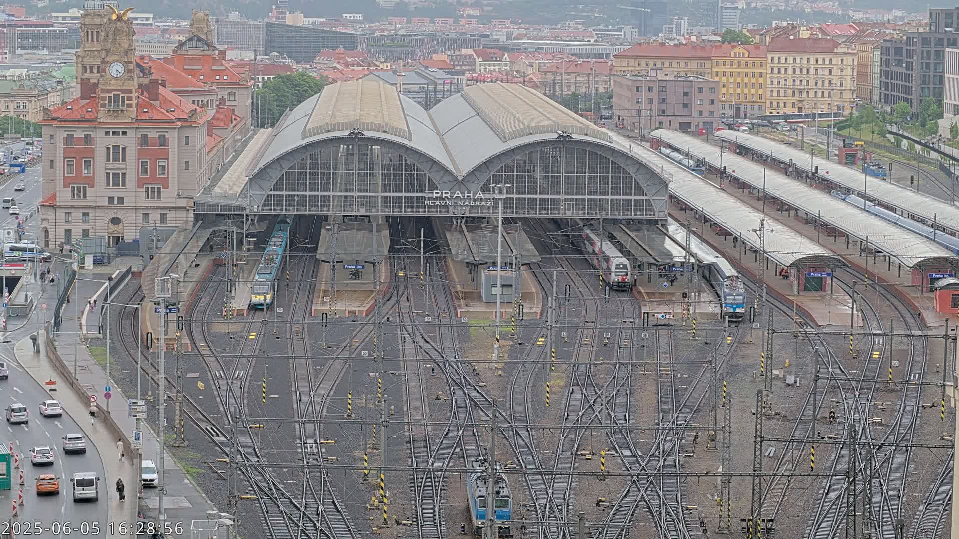 A large train station with numerous tracks, platforms, and trains, viewed from above on an overcast day.