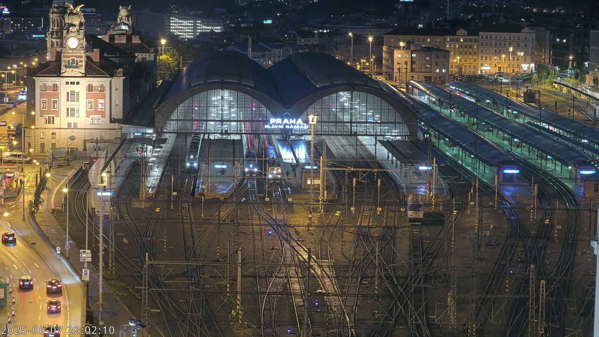 A nighttime aerial view of a large train station with many tracks and platforms, illuminated by artificial lights.