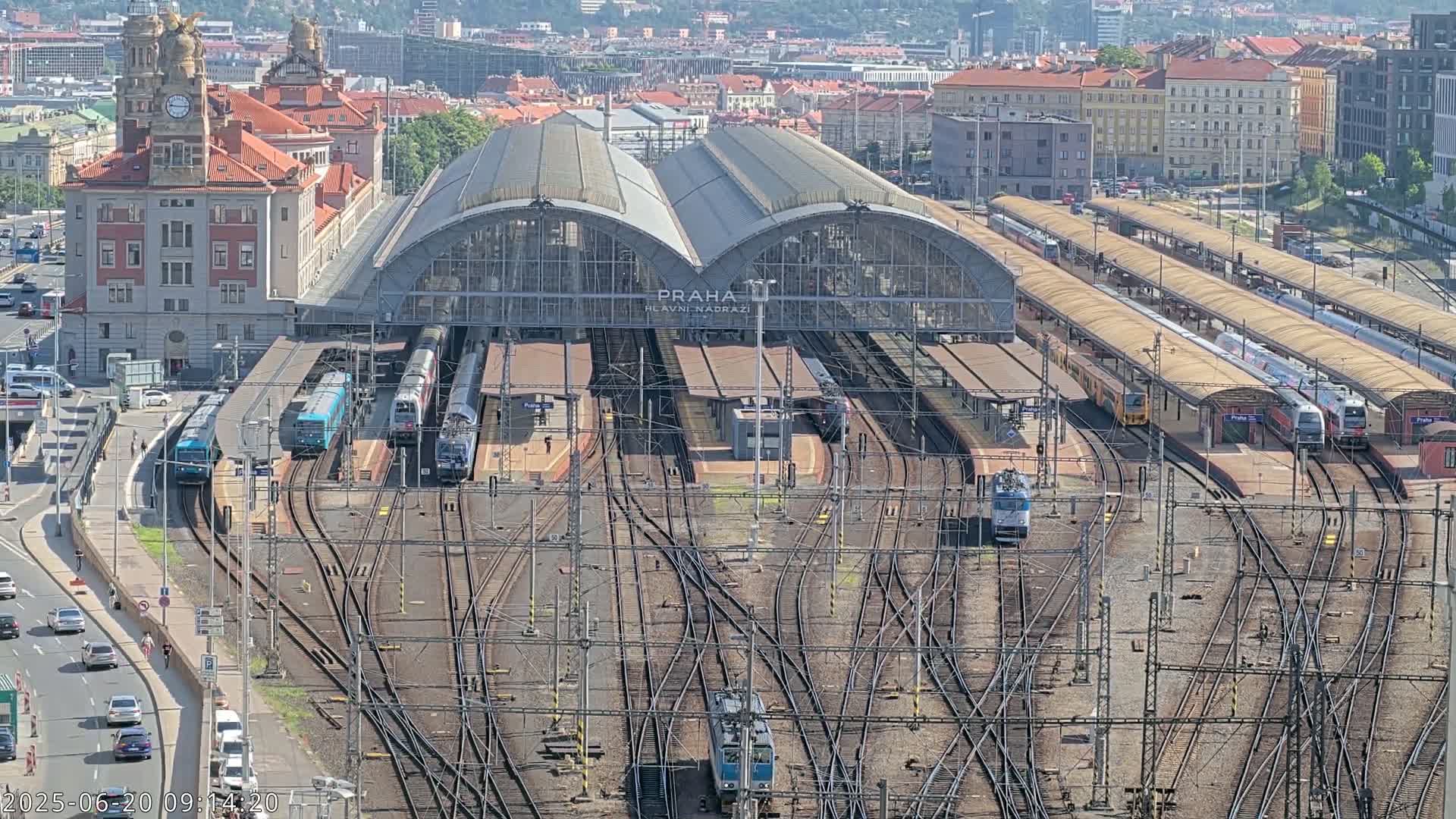 A large train station with numerous trains and tracks, under a sunny sky.