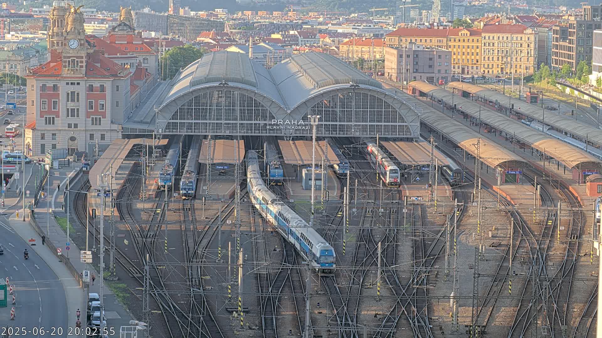 A large train station with numerous trains and tracks, under a clear evening sky.