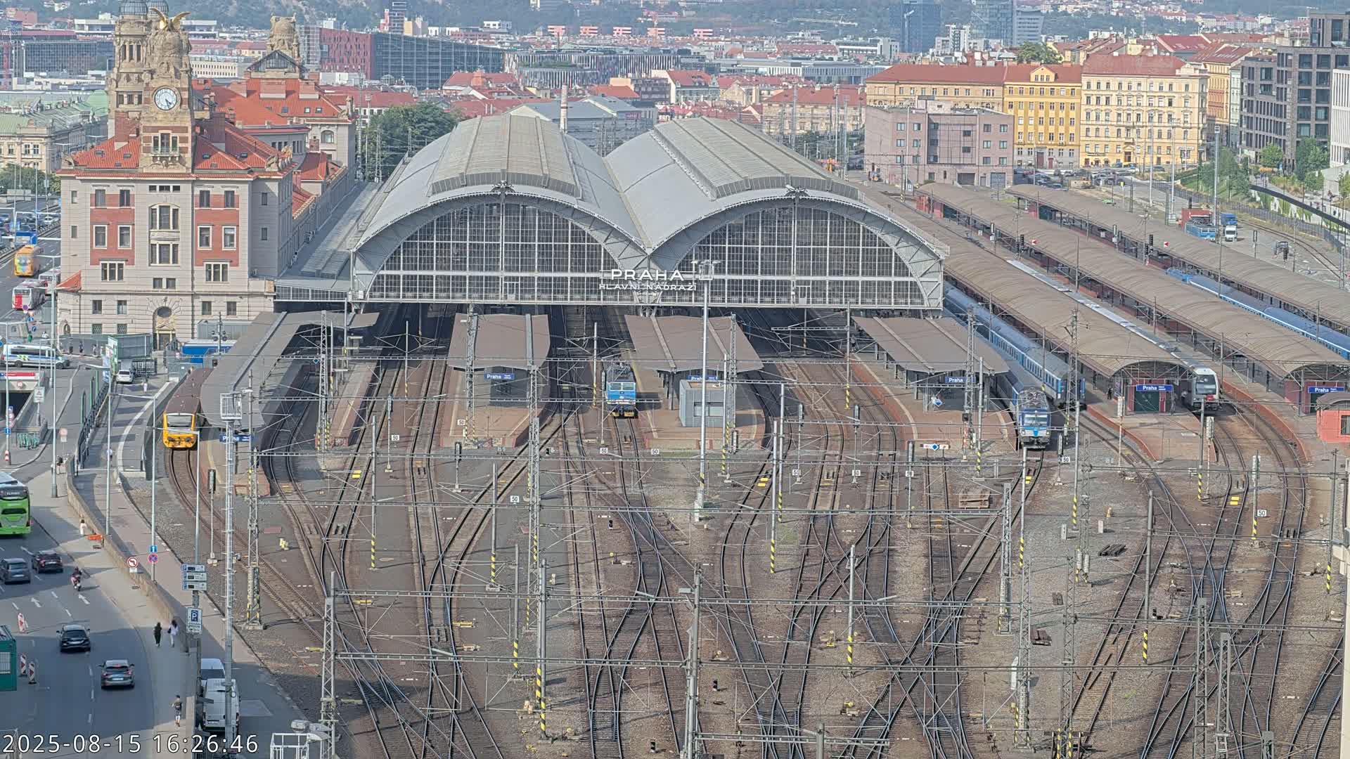 A large train station with many tracks and trains, viewed from above on a rainy day.