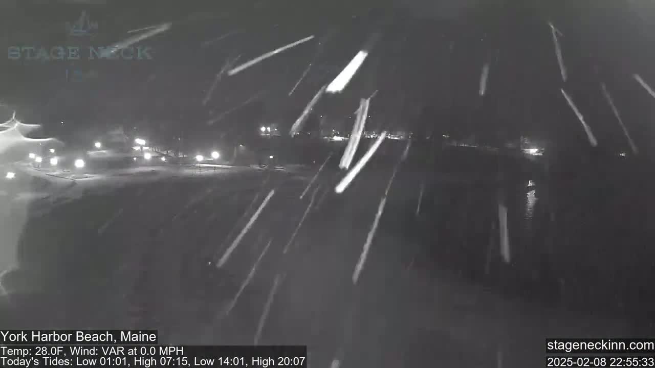 A nighttime snow scene shows a dark, snow-covered landscape with faint lights in the distance.