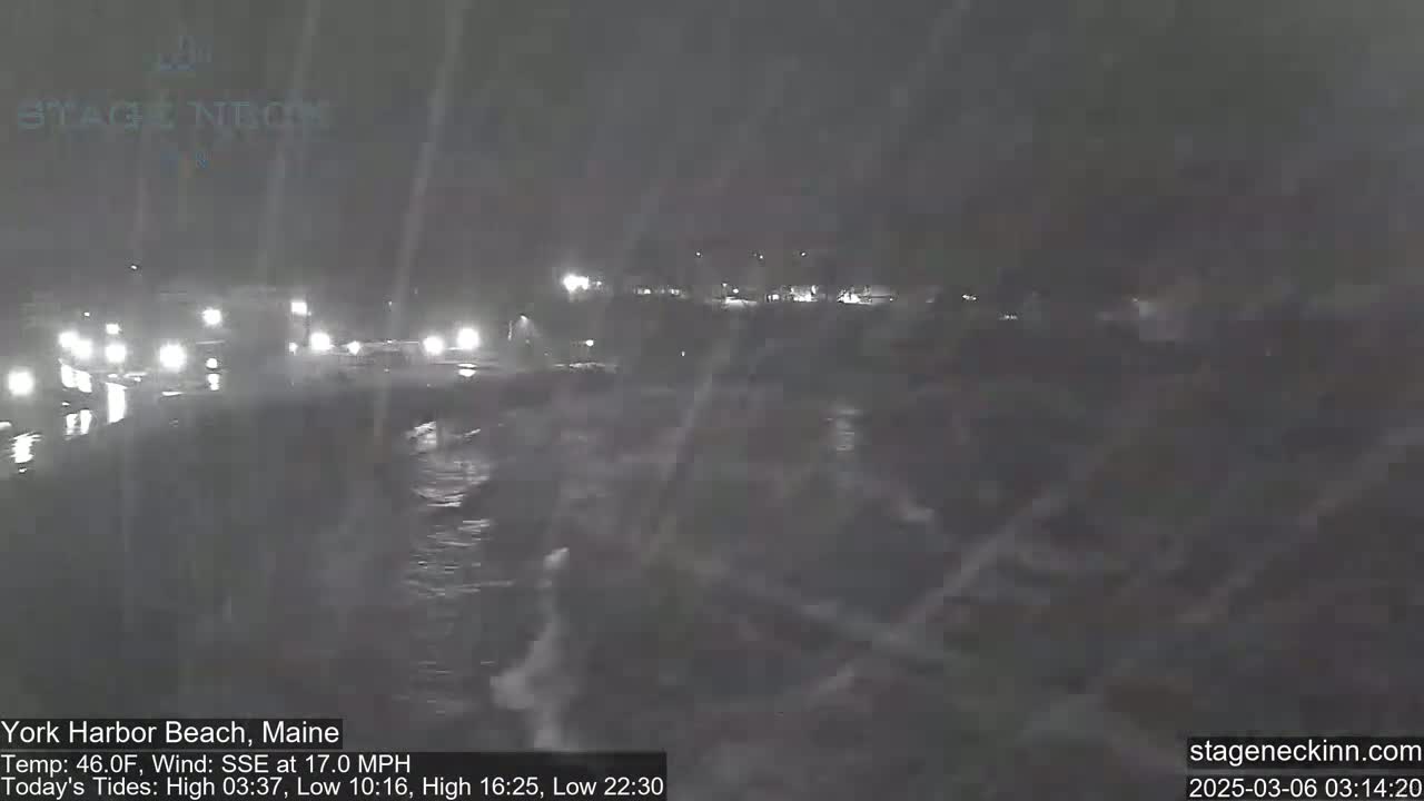 A nighttime scene of a road with cars driving through heavy snowfall.