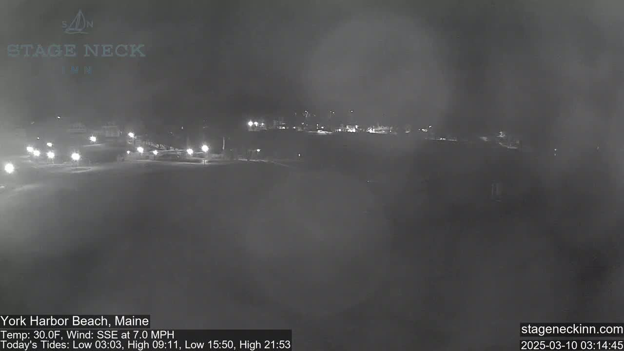 A nighttime, hazy view of a sparsely lit road and buildings under a 30°F temperature with a SSE wind at 7.0 mph.