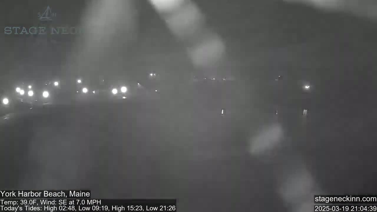 A foggy night scene shows several vehicles with their headlights on driving down a road.