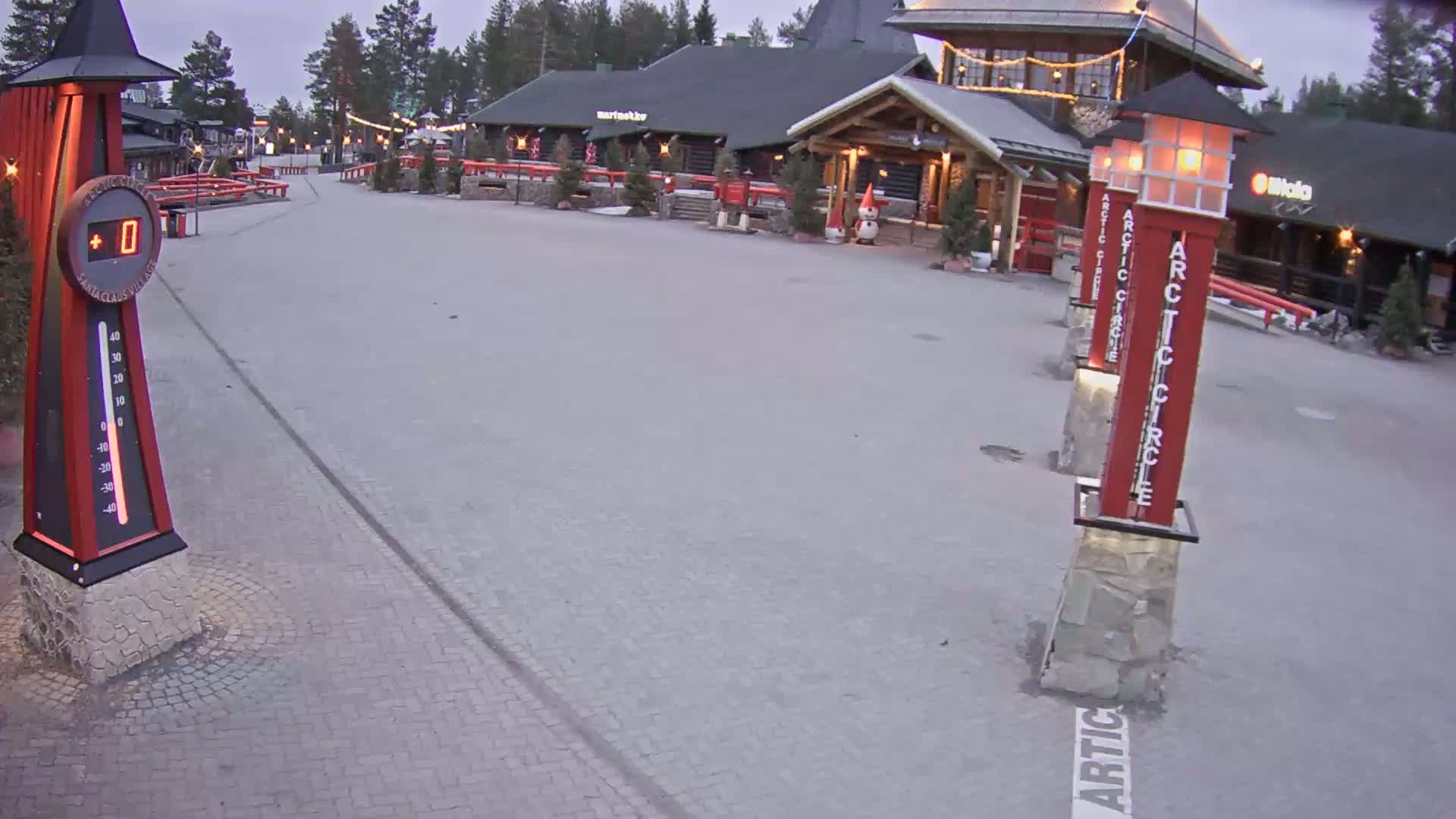 A snow-covered plaza with several wooden buildings and tall red columns is visible under a twilight sky.