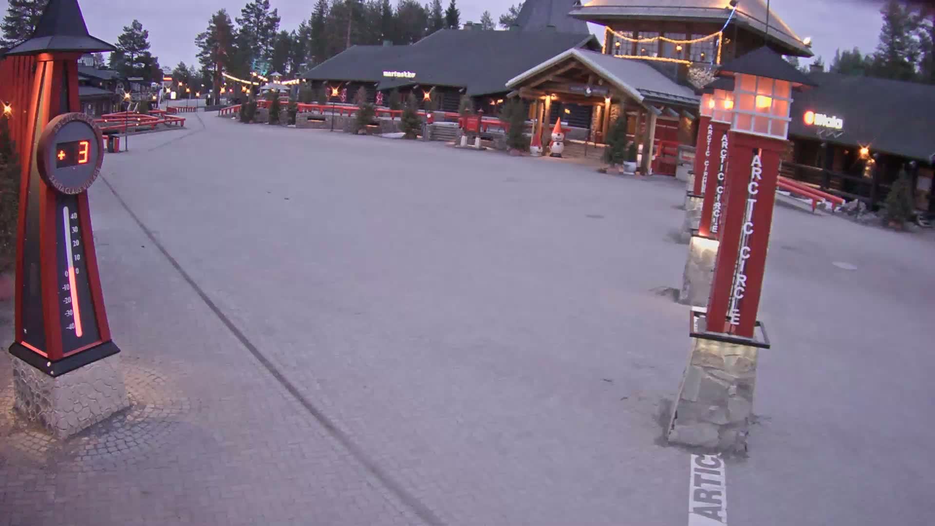 A paved area in front of a building complex shows a temperature of 3 degrees Celsius, under a twilight sky.