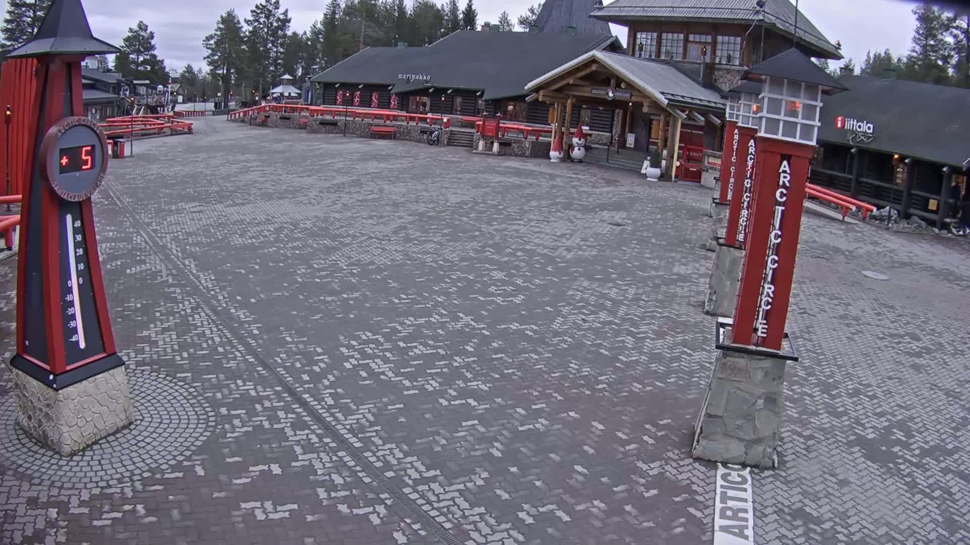 A paved plaza with several red Arctic Circle markers and a thermometer showing a temperature of 5 degrees, under an overcast sky.