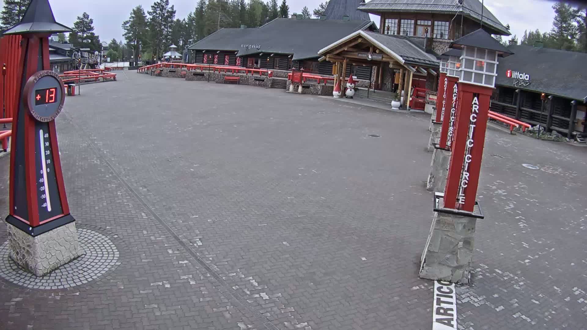 A brick plaza with a large log building and several red pillars displaying "Arctic Circle," under an overcast sky.